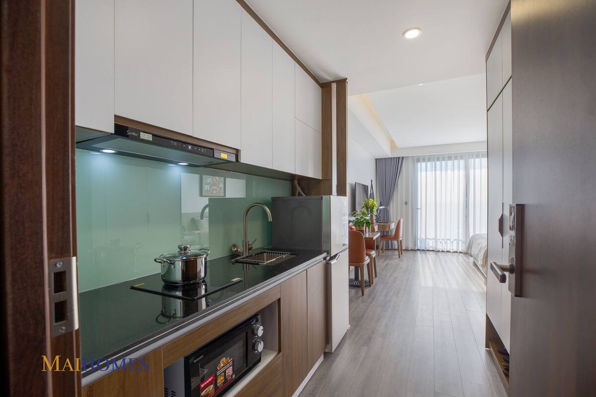 A modern kitchen with a built-in stove, sink, and a dining area with a table and chairs.
