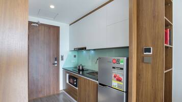 Cocina compacta con armarios de madera, refrigerador de acero inoxidable y horno integrado.