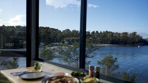 A dining table with food and a view of a lake and trees.