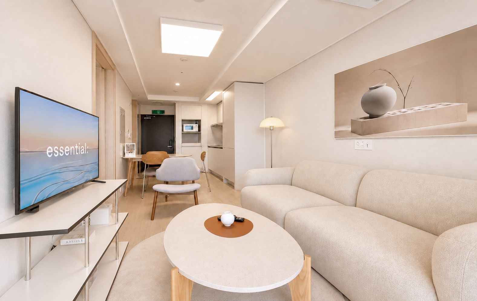 Ein modernes Hotelzimmer mit Flachbildfernseher, einer Sitzecke, einem runden Tisch und minimalistischer Einrichtung.