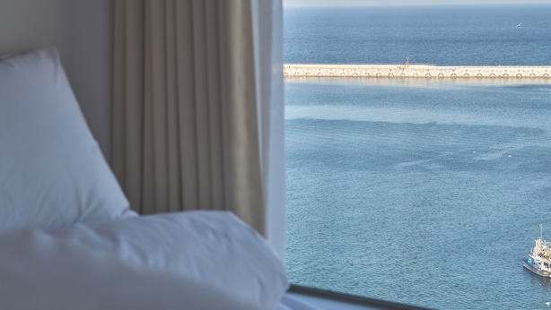 A hotel room with a large window overlooking a calm sea and a distant pier. - UH FLAT THE SOKCHO (Sokcho)