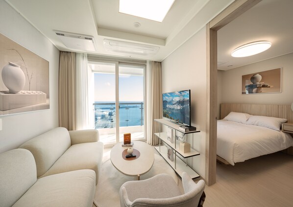 A modern hotel room with a large bed, a sofa, a coffee table, and a TV on a stand. - UH FLAT THE SOKCHO (Sokcho)