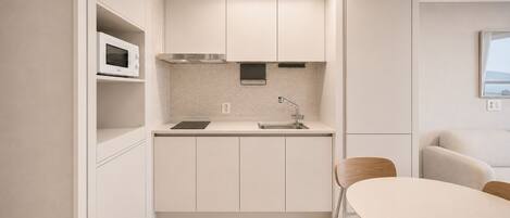 A compact kitchen with a microwave, stove, and sink.
