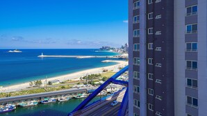 A high-rise hotel overlooking a coastal area with a marina, beach, and ocean. - UH FLAT THE SOKCHO (Sokcho)