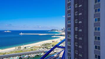 A high-rise hotel overlooking a coastal area with a marina, beach, and ocean.