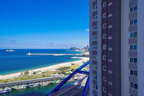 Un hotel moderno con vistas a la costa, con un puerto deportivo, playa y océano.