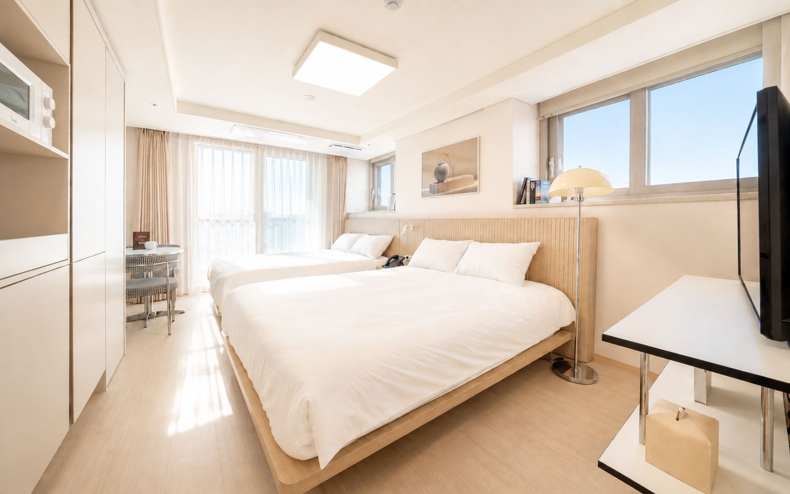 Habitación de hotel con una cama grande, mesitas de noche, un escritorio, una silla, un televisor y una ventana con cortinas.
