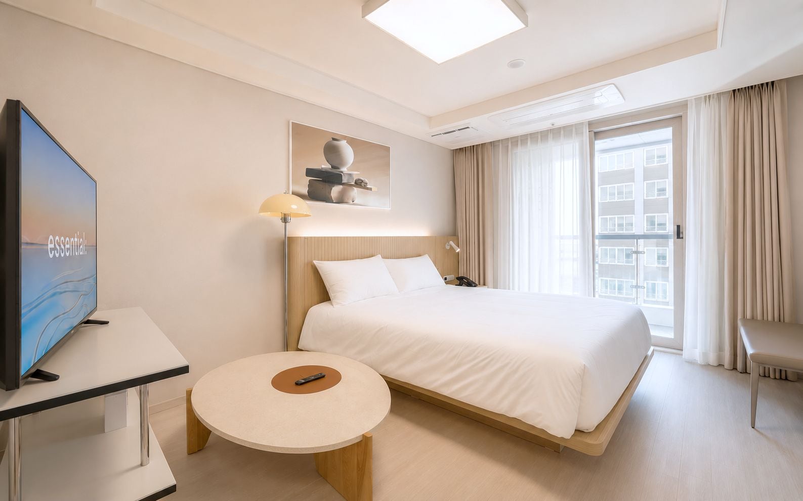 Una camera d'albergo con un letto, una scrivania, una televisione, una lampada e una finestra con tende.