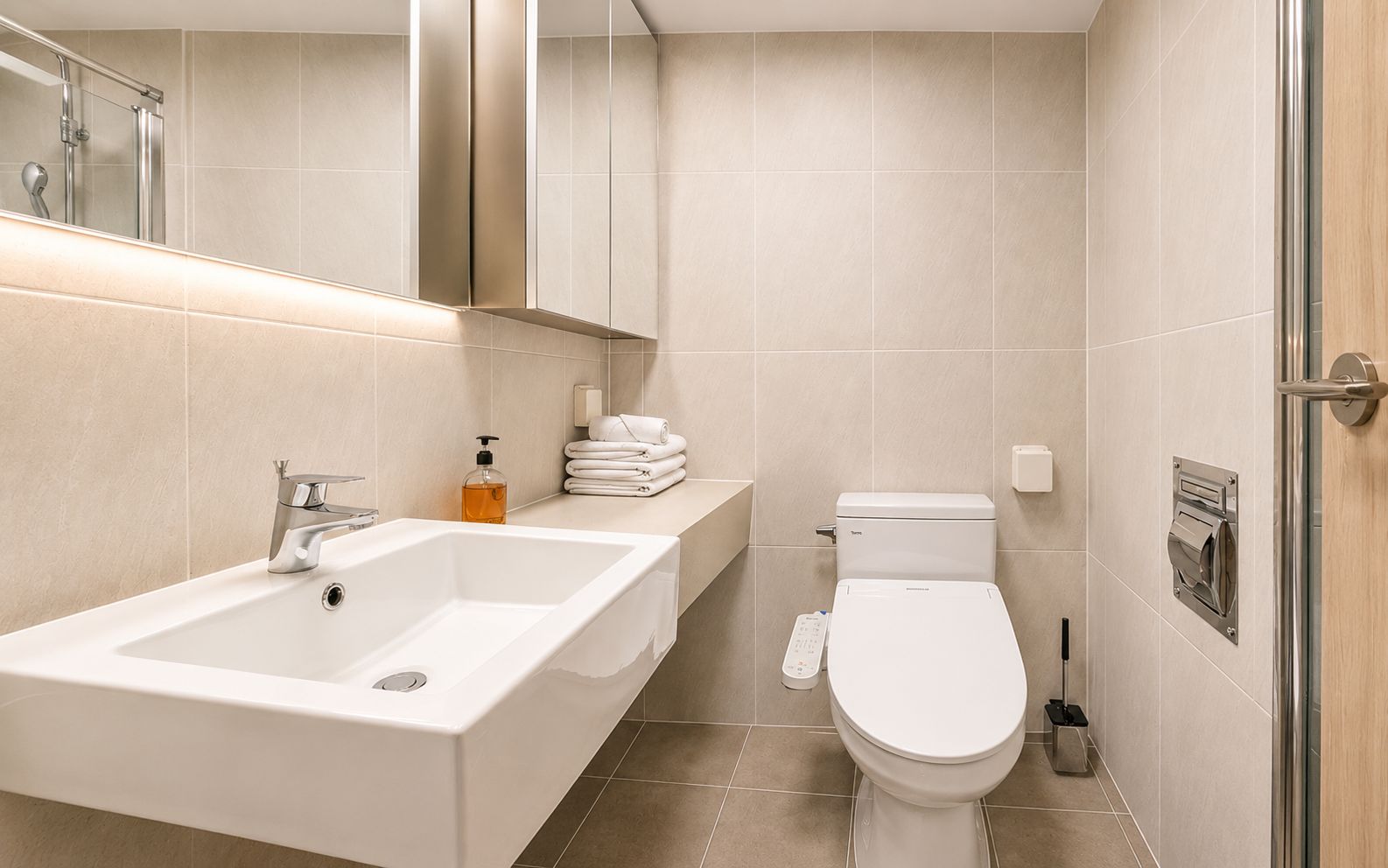 A modern bathroom with a white sink, a toilet, and a shower area.