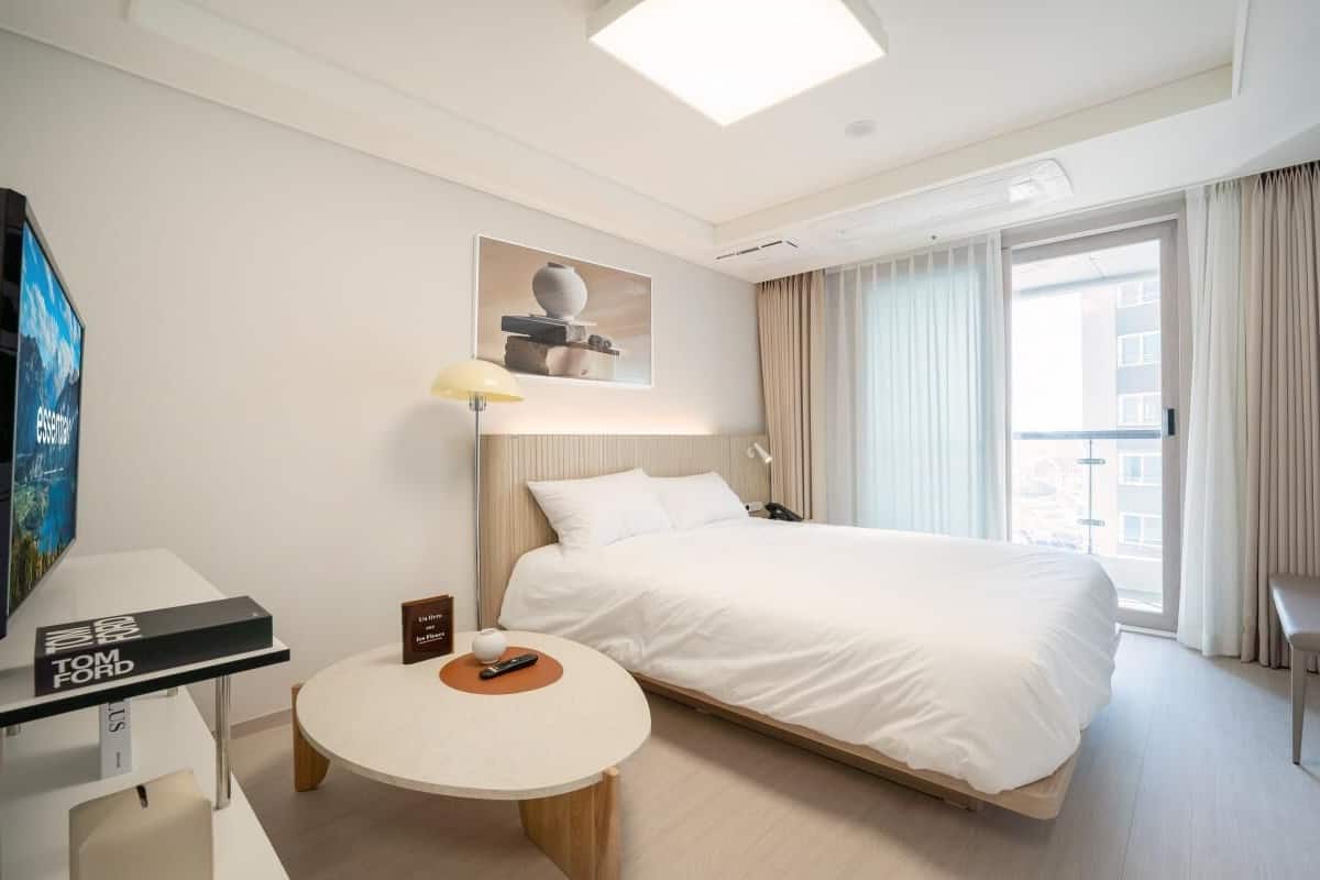 A hotel room with a bed, a round table, a TV, and a window with curtains.