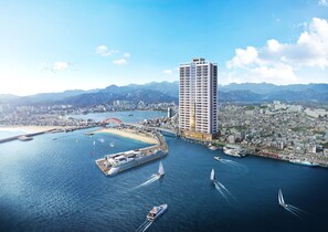 A high-rise hotel with a view of a coastal cityscape, including a bridge and mountains in the background. - UH FLAT THE SOKCHO (Sokcho)
