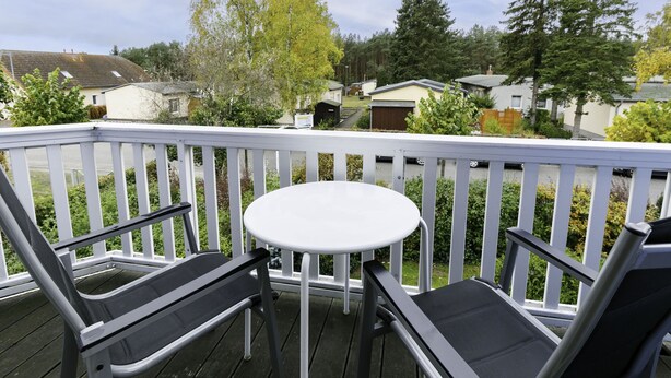 A balcony with a white railing, a small round table, and two black cushioned chairs. - Eickhus Weisse Wohnung by Interhome (Zinnowitz)