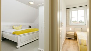 A bedroom with a bed, a nightstand, a window, and a door. - Eickhus Weisse Wohnung by Interhome (Zinnowitz)