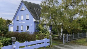 A blue house with the name 'Eichhus' on the side, a white fence, and a paved path leading to a gate. - Eickhus Weisse Wohnung by Interhome (Zinnowitz)