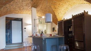 A kitchen with a brick ceiling, a central island with stools, and a refrigerator.