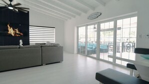 A modern living room with a grey sofa, a flat-screen TV, and a ceiling fan. - Waterfront Marathon Retreat ,Private Boat Dock & Lift ,Hot Tub ,Sleeps 8 (Marathon)
