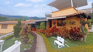 A house with a solar panel, a garden with various plants, and a bench. - Finca-Hostal Sanfelipe (Calima)