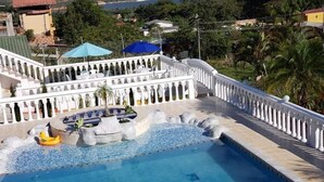 A swimming pool with a fountain, surrounded by a white fence and palm trees. - Finca-Hostal Sanfelipe (Calima)