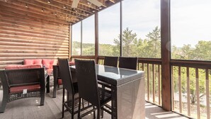 Un espacio al aire libre cubierto con mobiliario de mimbre, una mesa de vidrio y un ventilador de techo.