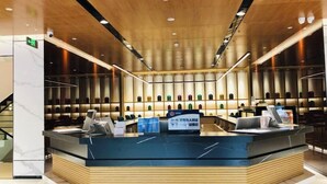 A modern hotel reception area with a central desk, a staircase to the left, and a wall of illuminated containers. - Hotel Yoo Beijing  (Beijing)