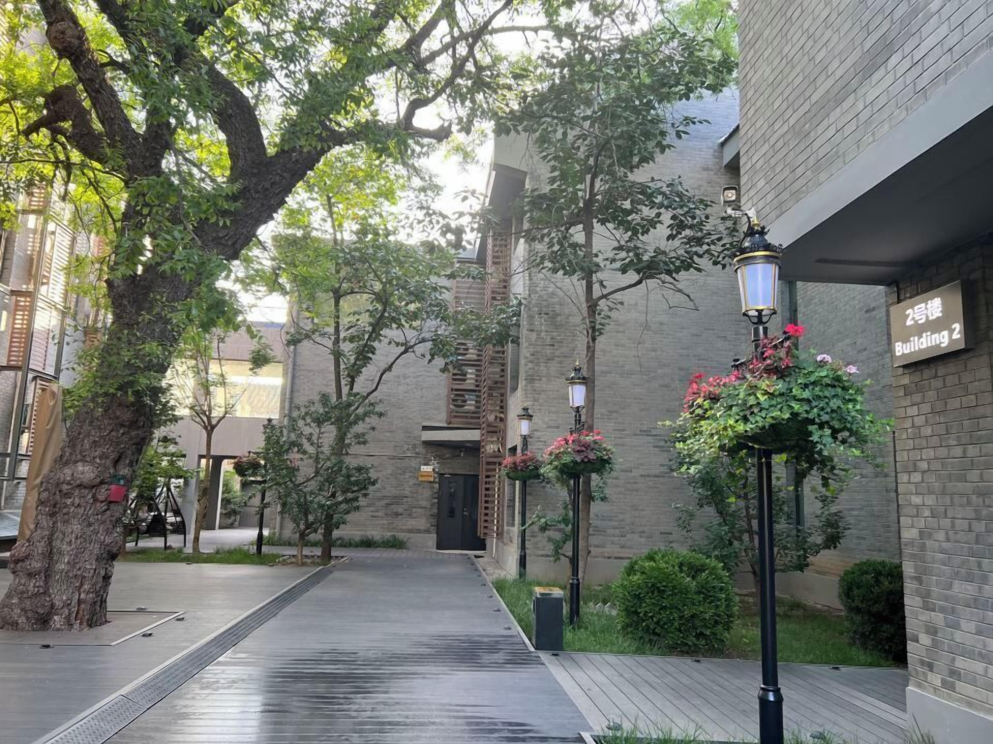 Un sendero bordeado por árboles y un edificio con un cartel que indica 