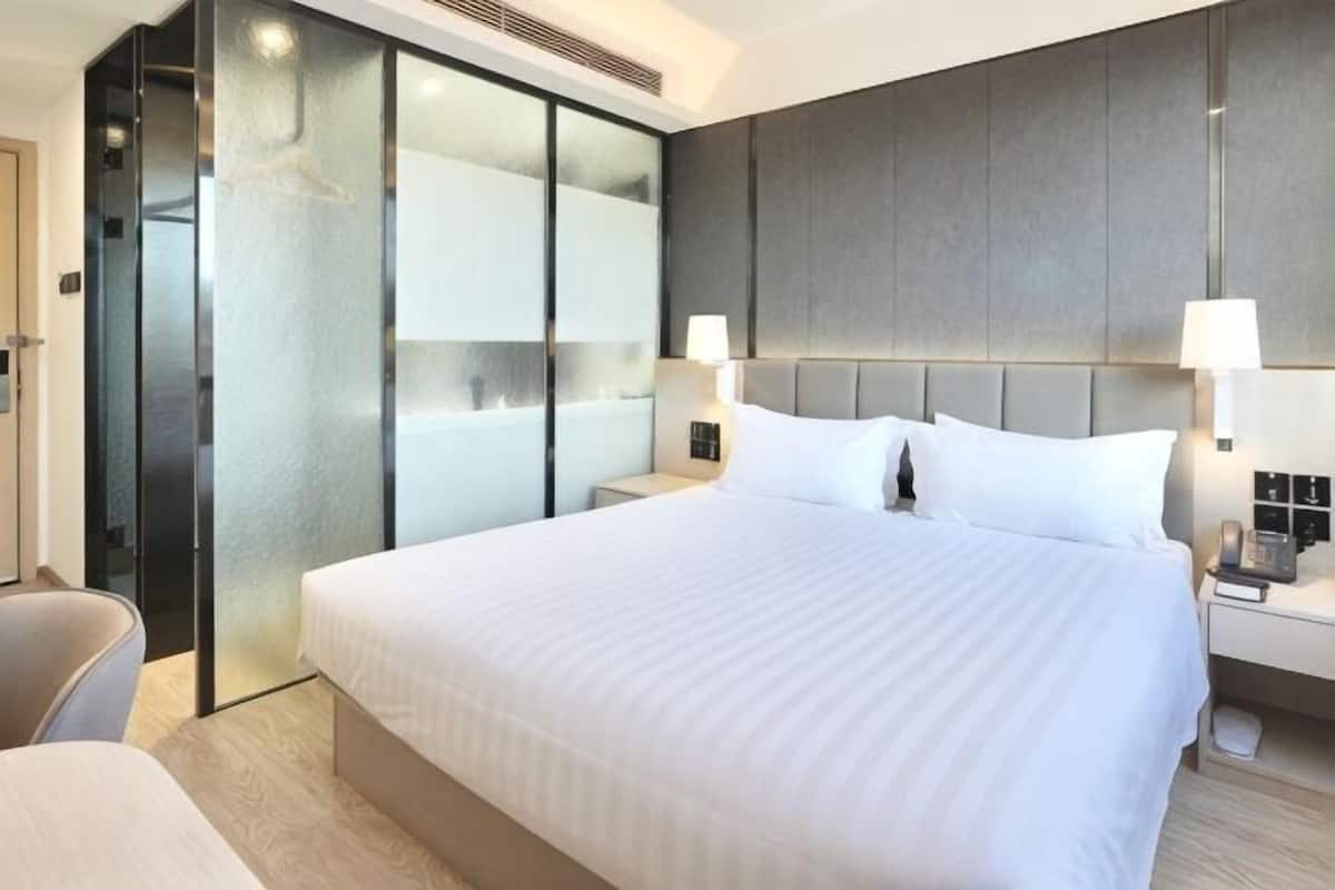 Una habitación de hotel con una cama grande, una mesita de noche con lámpara, un armario con puertas correderas y una silla.