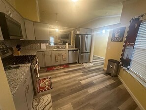 A modern kitchen with a central island, stainless steel appliances, and a tiled backsplash. - Charming 3 Bed 2 Bath Home in NE San Antonio (Converse)