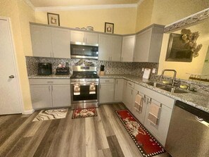 A compact kitchen with grey cabinets, a stainless steel oven, a microwave, and a coffee maker.