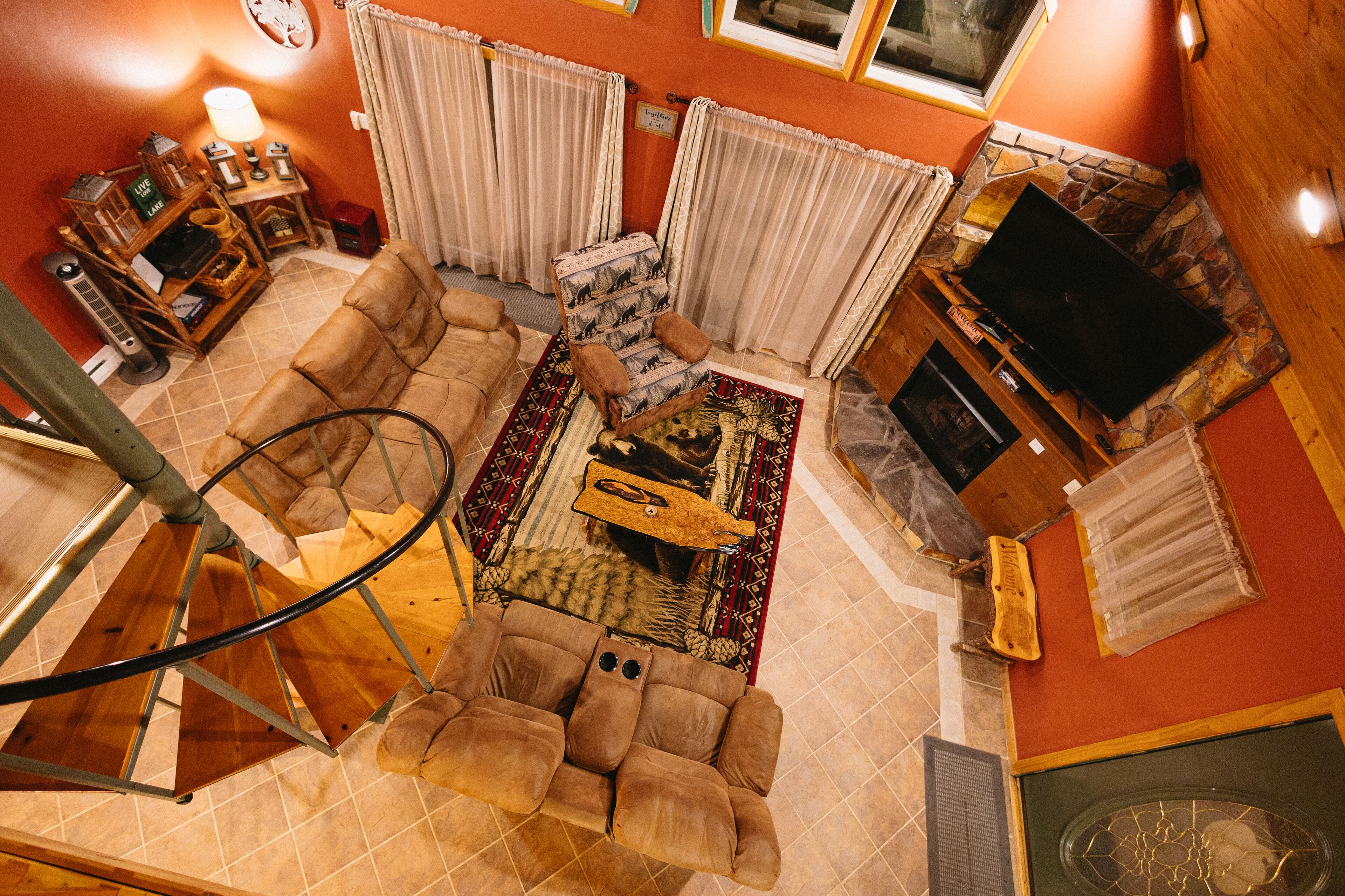 Un salon avec un canapé, un téléviseur, une cheminée et un escalier.