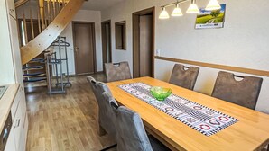 Ein Essbereich mit einem Holztisch, Stühlen und einer Treppe.