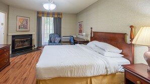 Una habitación de hotel con una cama grande, un escritorio, una silla, una lámpara y una chimenea.