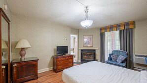 Un dormitorio con cama, cómoda, televisor y chimenea.
