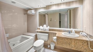 Un baño moderno con bañera, inodoro, lavamanos y un espejo grande.