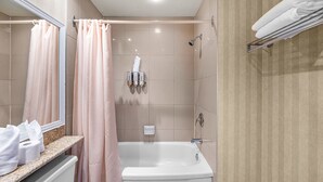 A bathroom with a bathtub, a shower, a towel rack, and a toilet paper holder.