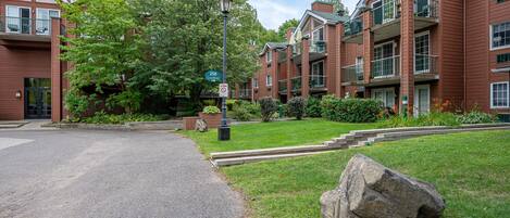 A brick building with balconies, a street lamp, and a large rock in the foreground.