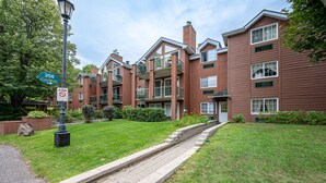 A multi-story brick building with balconies, a green lawn, and a sidewalk leading to the entrance.