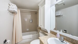 A bathroom with a bathtub, toilet, sink, and a mirror.