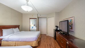 A hotel room with two beds, a television, a dresser, and a door leading to another room.
