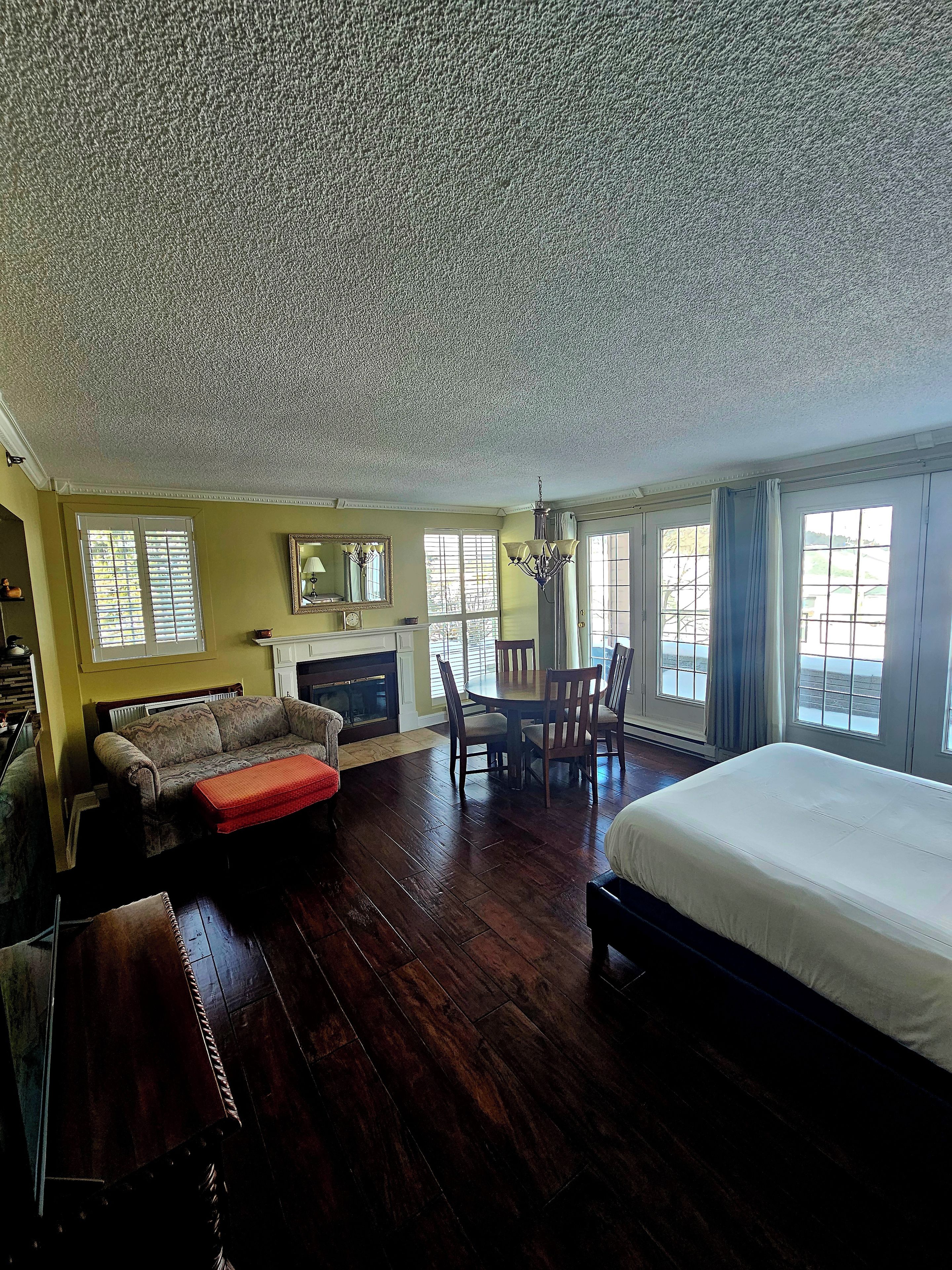A spacious room with a large bed, a dining table with chairs, a sofa, and a fireplace.