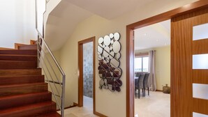 A modern interior with a wooden staircase, a decorative wall piece, and a dining area with a view. - Triplex Vilamoura VIP Properties by Interhome (Vilamoura)