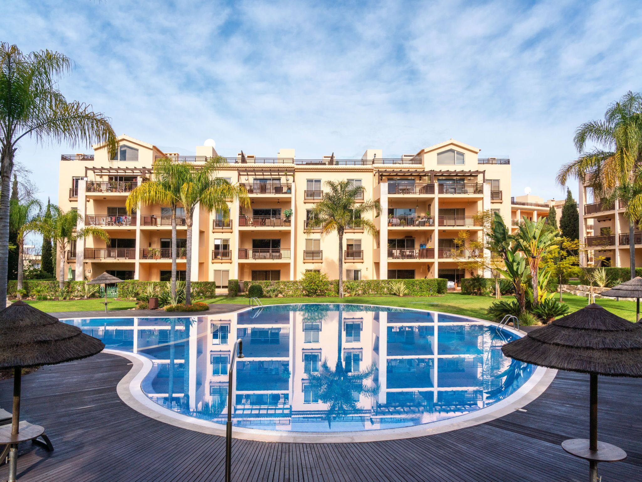 A resort with a swimming pool, multiple balconies, and tropical landscaping.