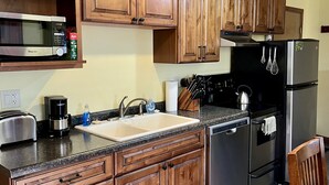 Une cuisine dotée de meubles de rangement en bois, d’un four à micro-ondes, d’une machine à café, d’un évier et d’un réfrigérateur.