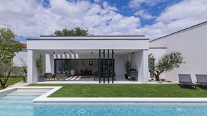 Ein modernes Haus mit Swimmingpool, Sitzgelegenheit im Freien und einer Terrassenfläche.