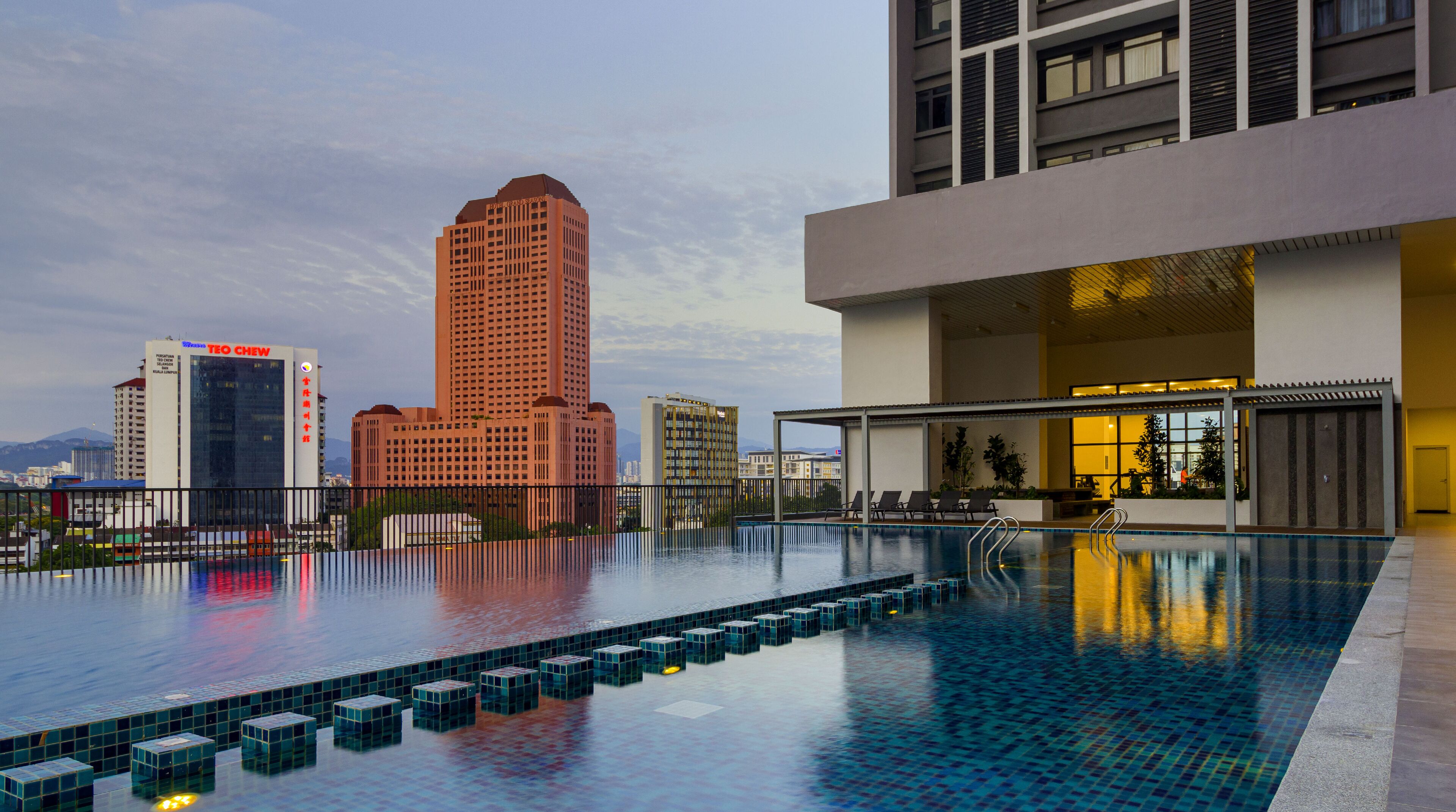 A rooftop pool with a cityscape view, including a prominent hotel building.