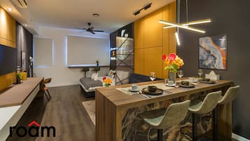 A modern kitchen with a marble island, bar stools, and a dining area with a table set for two.