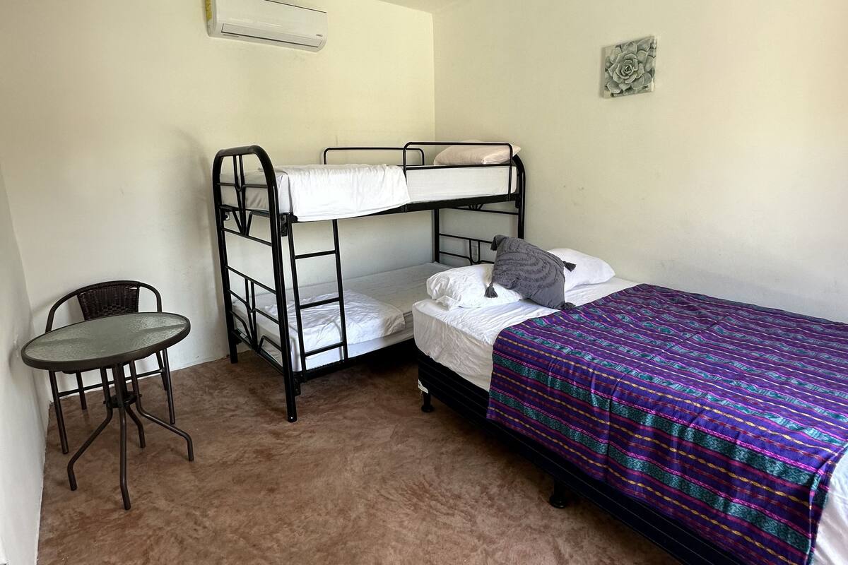 Una habitación con literas, una mesita y una lámpara colgante.