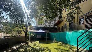 A courtyard with a green tent, a staircase, and a tree providing shade. - Hotel Thimphu Central (Thimphu)