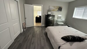 A bedroom with a bed, dresser, and a door leading to another room. - Insta-Worthy! Just Remodeled! Private Home! Luxurious & Brand New  (San Bernardino)