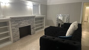 A living room with a stone fireplace, a black sofa, and a decorative mirror. - Insta-Worthy! Just Remodeled! Private Home! Luxurious & Brand New  (San Bernardino)