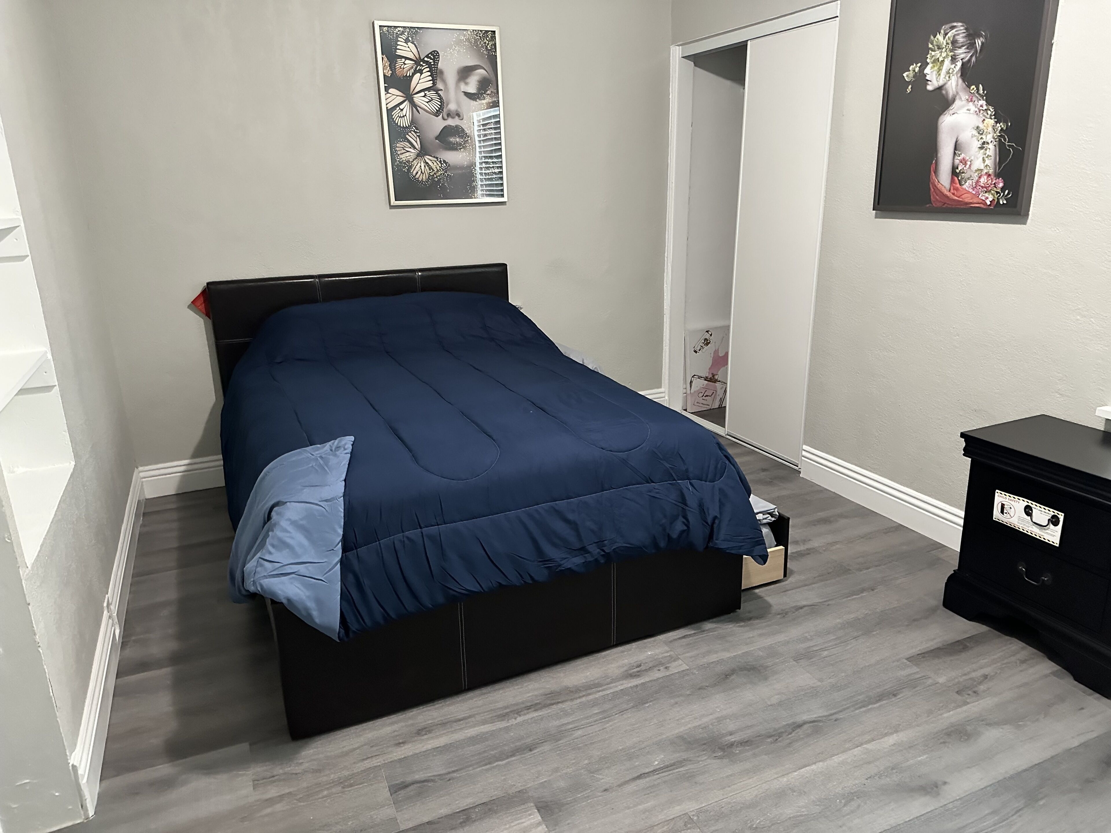 Ein Schlafzimmer mit einem Bett, einer Kommode und zwei gerahmten Bildern an der Wand.